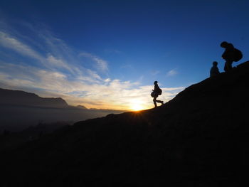 Silhouette people standing on mountain against sky during sunset
