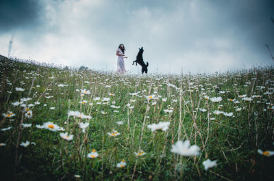 Woman and dog standing on field against sky