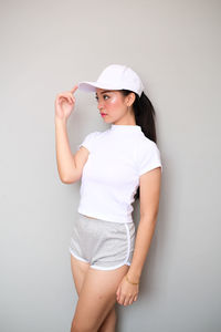 Young woman wearing hat standing against white background