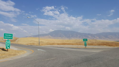Road signs on roadside against sky at desert