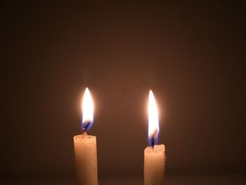 Close-up of burning candle against black background