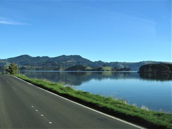 Road by lake against blue sky