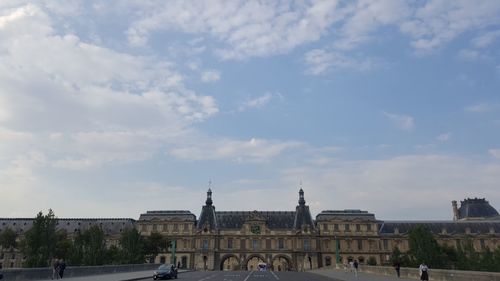 Buildings in city against cloudy sky