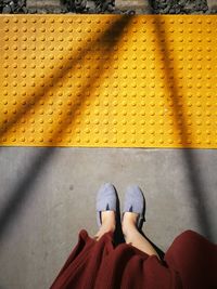 Low section of woman standing on railroad station platform