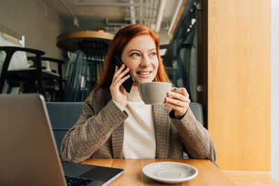 Young woman using laptop while sitting on table