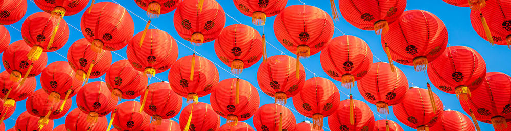 Low angle view of lantern hanging in row against sky