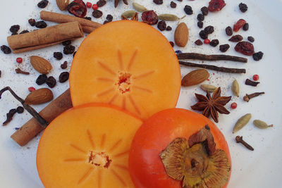 High angle view of various spices and persimmon on table