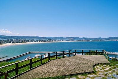 Pier over sea against clear blue sky