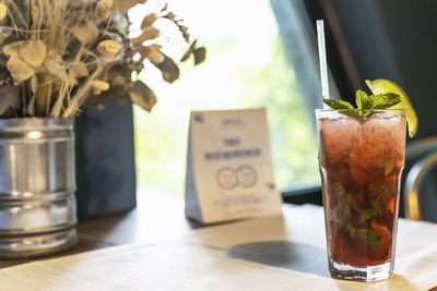 Refreshing cocktail with a straw on the table by the window in the cafe.