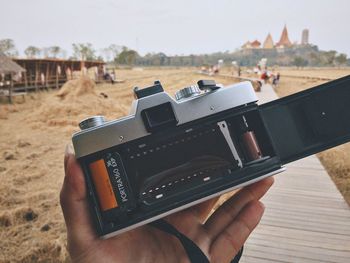 Close-up of human hand holding camera on field