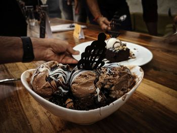 Close-up of hand holding ice cream on table