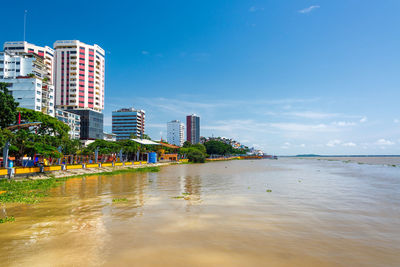 View of buildings by river against sky