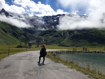 Woman standing on road leading towards mountains 