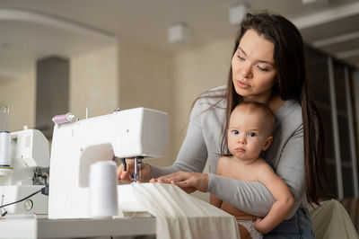 Mother sewing while sitting with son at home