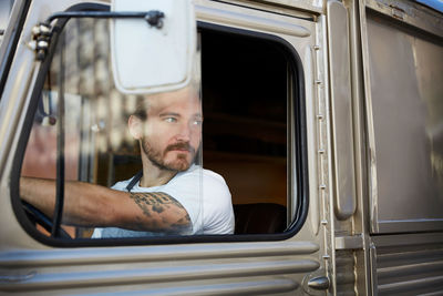 Young man looking out the window while driving food truck in city