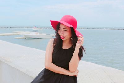 Beautiful young woman standing at beach against sky