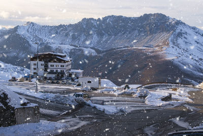 Snow covered houses by mountain against sky