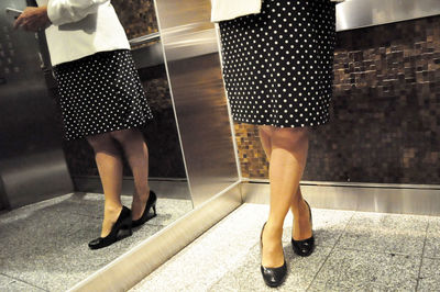 Low section of business woman using smart phone in elevator