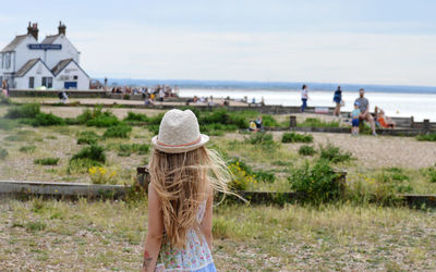 Rear view of girl on grass against sea and sky