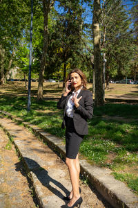 Portrait of young woman standing against trees