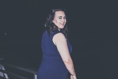 Portrait of smiling woman standing outdoors at night