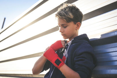 Boy wearing boxing strap while standing outdoors