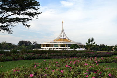 View of flowering plants in park against cloudy sky