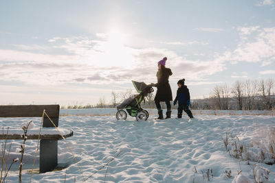 Woman and child walking in the snow with a stroller
