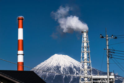 Industrial smokestack against view of mount fuji