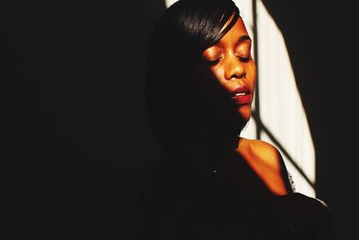 Portrait of young woman against black background