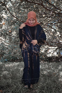 Portrait of young woman standing on snow covered field