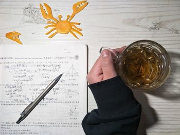 Cropped hand having drink while studying at table