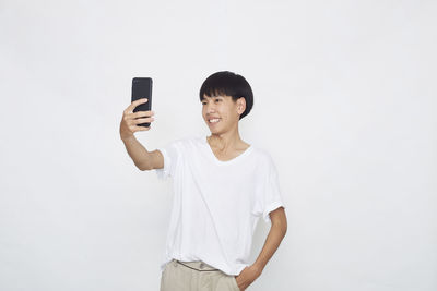 Young man using mobile phone against white background