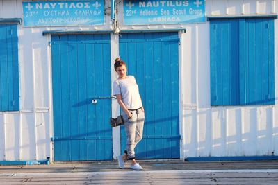 Woman standing against closed blue doors