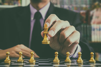 Midsection of man playing with chess against blurred background