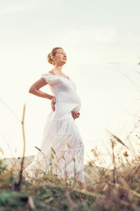 Woman with arms raised on field against sky