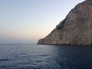 Rock formations by sea against clear sky