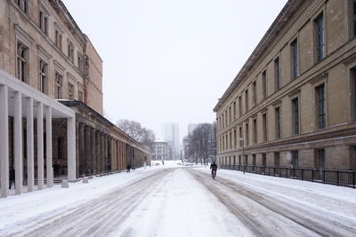 Road amidst buildings in city against clear sky