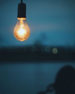 Close-up of illuminated light bulb against sky