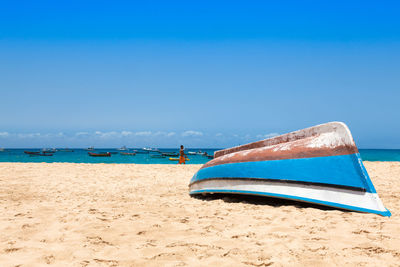 Deck chairs on beach against blue sky