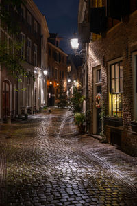 Wet street amidst buildings at night