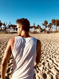 Rear view of man standing at beach against sky