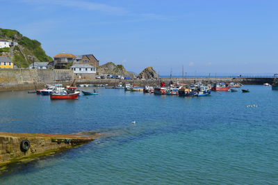 Sailboats in sea by buildings against sky