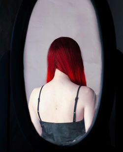 Rear view of woman with red hair reflecting in mirror