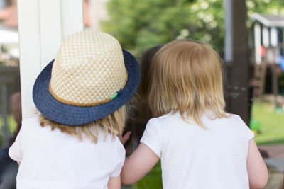 Rear view of girls standing against glass at park