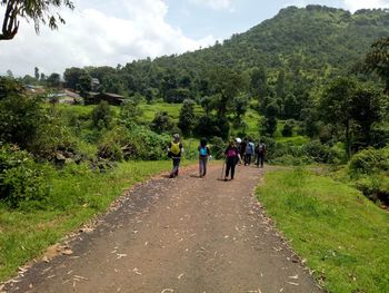 Rear view of people walking on mountain road