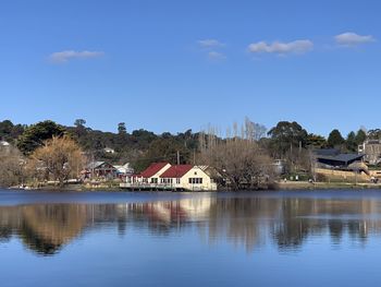 Houses by lake and buildings against blue sky