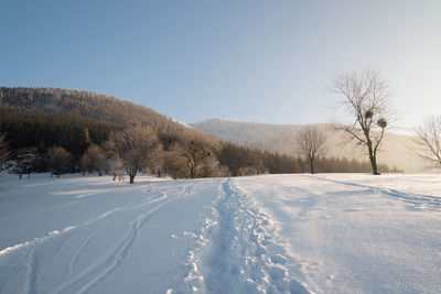 Snow covered field against clear sky