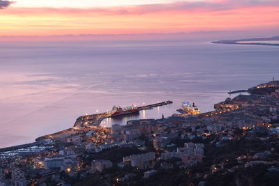 High angle view of buildings by sea against sky during sunset