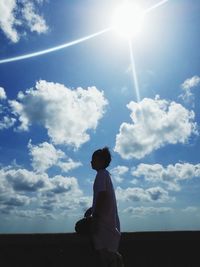 Silhouette woman standing against sky on sunny day